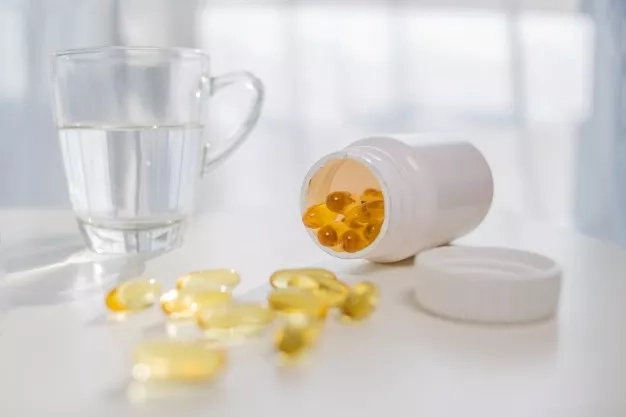 nutritional supplements with cod liver oil capsules and water glass