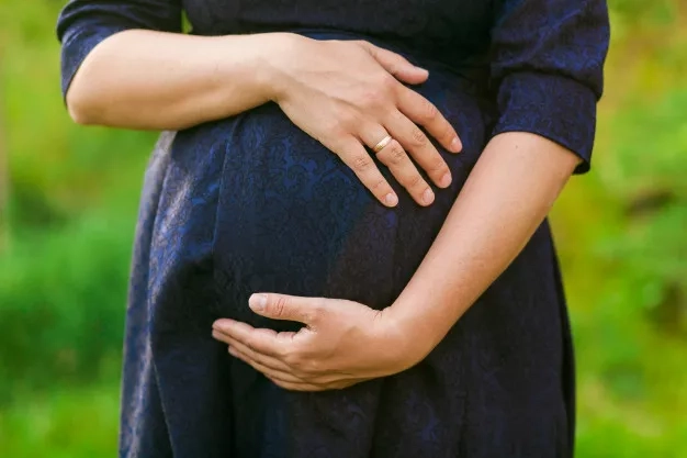 pregnant woman in black and blue dress standing outdoors